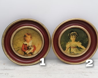 May include: Two framed portraits of children. The portrait on the left features a girl in a red dress holding a small dog. The portrait on the right features a girl in a white dress with a pink sash.