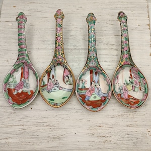 Könnte beinhalten: Set aus vier Suppenlöffeln aus Porzellan mit goldenen Verzierungen und farbenfrohen handbemalten Szenen von Menschen in traditioneller chinesischer Kleidung.