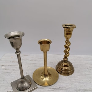 Può includere: Tre portacandele, uno argentato e due dorati. Il portacandele argentato ha una base quadrata e uno stelo alto e sottile. I portacandele dorati hanno basi rotonde e design dello stelo diversi.