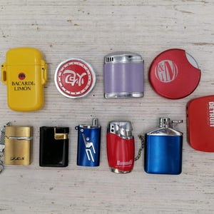 Puede incluir: Una colecci&oacute;n de diez encendedores, incluyendo un encendedor amarillo con el texto "Bacardi Limon", un encendedor morado, un encendedor rojo con el texto "&M", un encendedor rojo con el texto "DETROIT", un encendedor negro, un encendedor azul con un dise&ntilde;o de persona, un encendedor rojo con el texto "Dupont", un encendedor azul y dos encendedores redondos con dise&ntilde;os.