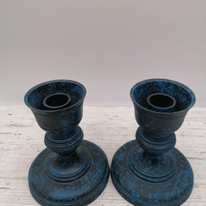 Può includere: Due candelabri dipinti di blu e nero. Ogni portacandela ha una base rotonda, uno stelo decorativo e una parte superiore svasata per una candela. I portacandele hanno una finitura usurata e strutturata.