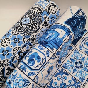 Puede incluir: Dos rollos de tela con patrones inspirados en azulejos azules y blancos. Un rollo muestra motivos geométricos, mientras que el otro presenta ilustraciones de un gallo, un puente y el texto Porto y Portugal en una disposición de cuadrícula.