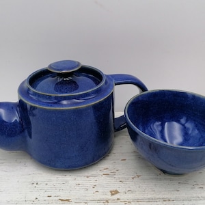Könnte beinhalten: Eine blaue Teekanne und eine passende Teetasse aus Keramik. Die Teekanne hat einen Deckel und einen Henkel. Die Teetasse ist rund und hat einen leichten Rand.