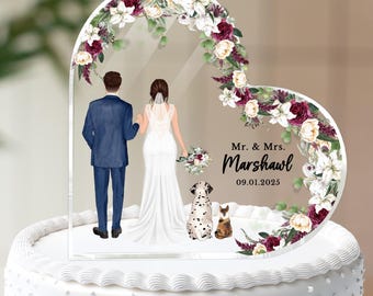 Könnte beinhalten: Ein herzförmiger Tortenaufsatz für eine Hochzeit mit einer Illustration von Braut und Bräutigam, Blumenschmuck und den Namen "Mr. & Mrs. Marshawl" mit Datum. Der Aufsatz befindet sich auf einer weißen Torte mit dekorativen Punkten.