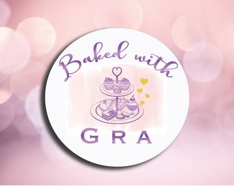 May include: A white circle with the text "Baked with GRA" in purple script. A purple illustration of a tiered cake stand with cupcakes, pastries, and a dessert in a glass dish is in the center of the circle.