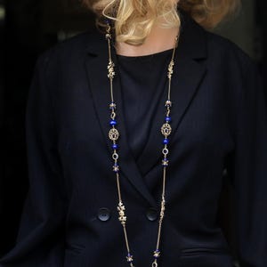 May include: A long gold chain necklace with blue and gold accents. The necklace features a floral design and blue beads.