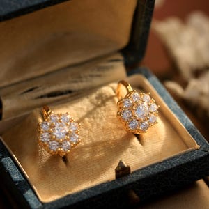 Puede incluir: Un par de pendientes de oro con un dise&ntilde;o de flor engastado con piedras transparentes brillantes. Los pendientes est&aacute;n en una peque&ntilde;a caja de terciopelo.