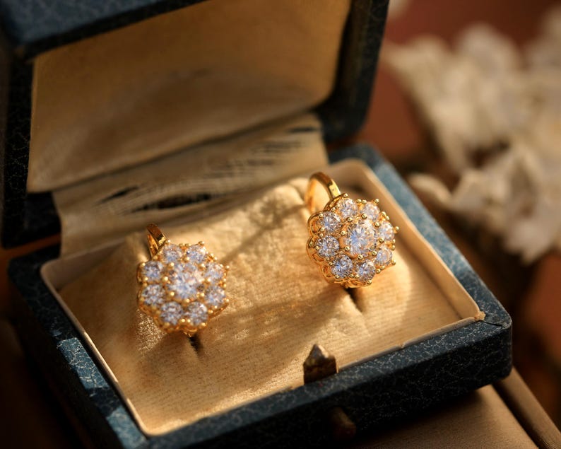 Puede incluir: Un par de pendientes de oro con un dise&ntilde;o de flor engastado con piedras transparentes brillantes. Los pendientes est&aacute;n en una peque&ntilde;a caja de terciopelo.