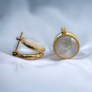 May include: A pair of gold hoop earrings with a white mother-of-pearl inlay.