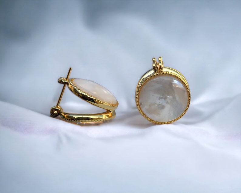 May include: A pair of gold hoop earrings with a white mother-of-pearl inlay.