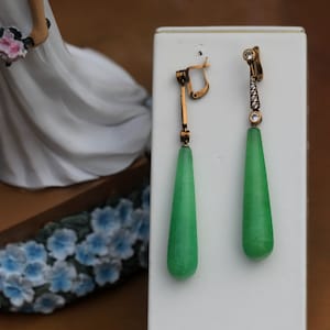 Può includere: Un paio di orecchini pendenti in giada verde con montatura in oro e dettagli in cristallo trasparente.