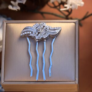 May include: A silver hair comb with a decorative design of clear crystals. The comb has five prongs.