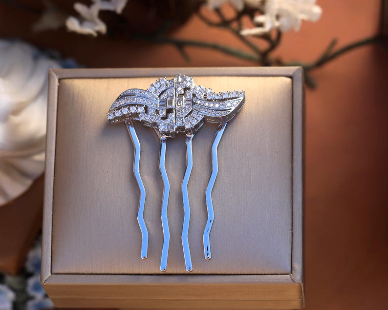 May include: A silver hair comb with a decorative design of clear crystals. The comb has five prongs.