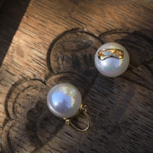 May include: A pair of pearl earrings with gold clasps. The pearls are white and iridescent.