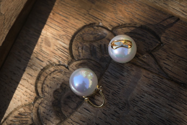 May include: A pair of pearl earrings with gold clasps. The pearls are white and iridescent.