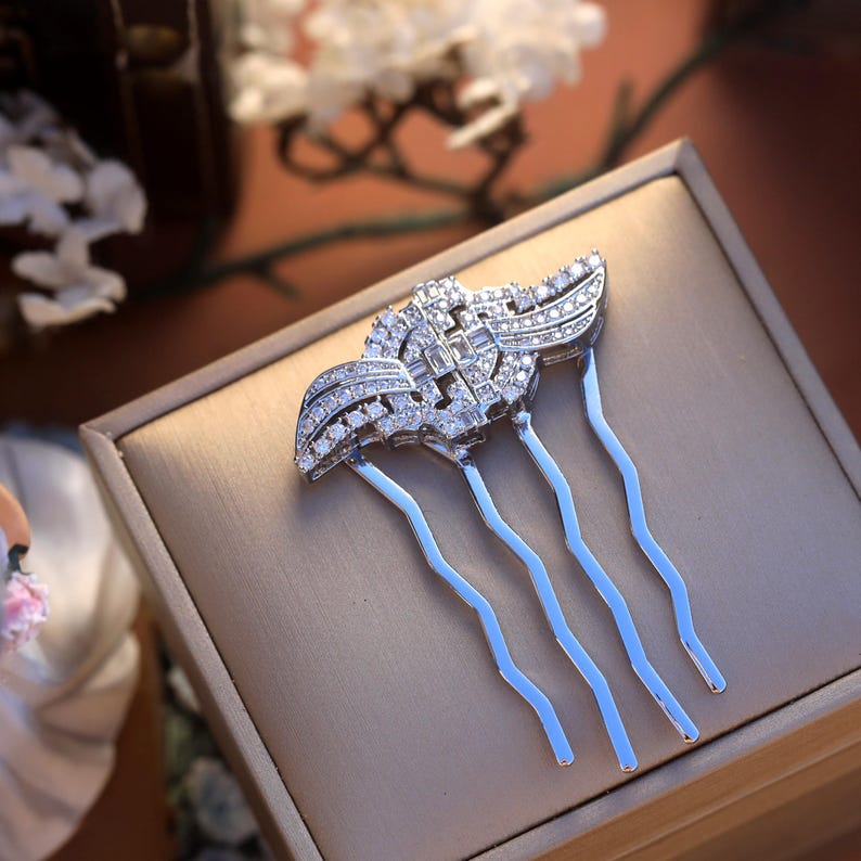 May include: Silver hair comb with a decorative design of clear cubic zirconia stones. The comb has five prongs.