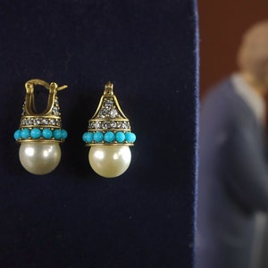 May include: A pair of gold earrings with a pearl drop, turquoise beads, and clear rhinestones.
