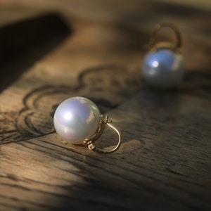 May include: A pair of pearl earrings with gold hoops. The pearls are white and iridescent.