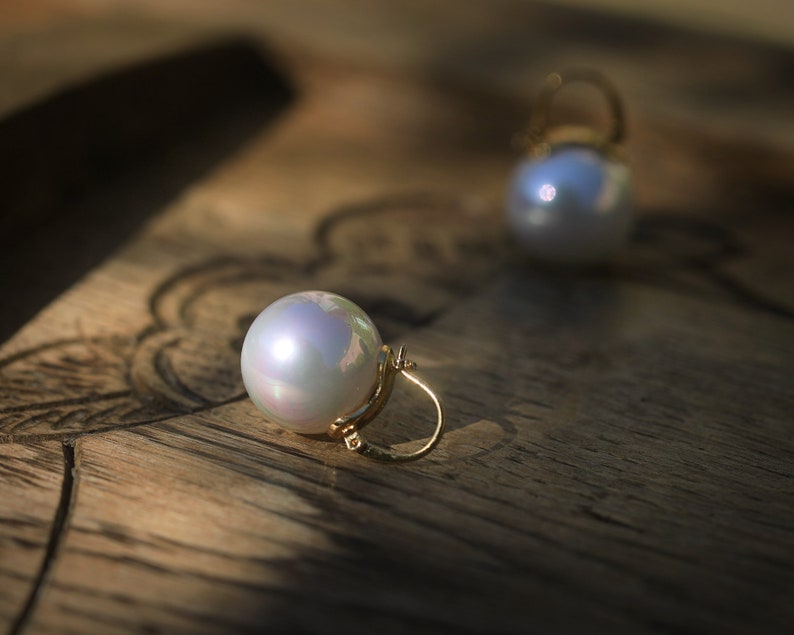 May include: A pair of pearl earrings with gold hoops. The pearls are white and iridescent.