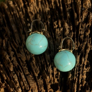 May include: A pair of gold hoop earrings with turquoise blue round stones. The stones have a marbled pattern.