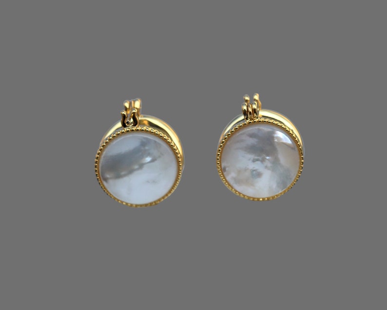 May include: A pair of gold-tone earrings with round white mother-of-pearl insets.