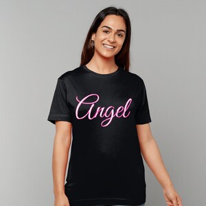 Peut inclure: T-shirt noir avec un graphique rose "Angel" en écriture cursive.