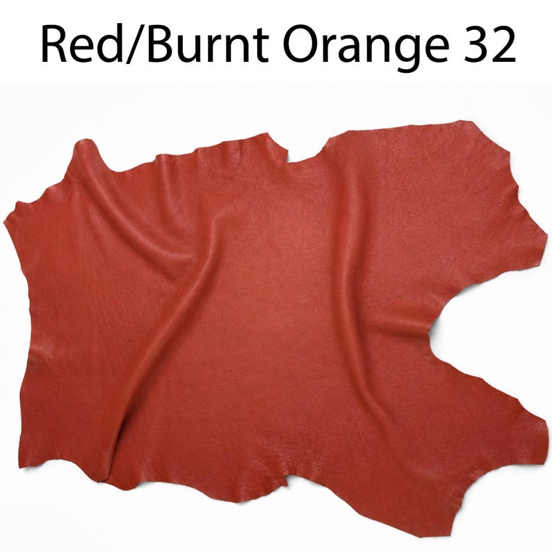 K&ouml;nnte beinhalten: Ein St&uuml;ck rotes und orangefarbenes Leder mit einer nat&uuml;rlichen, unregelm&auml;&szlig;igen Form und einer strukturierten Oberfl&auml;che. Der Text "Red/Burnt Orange 32" ist oben im Bild in Schwarz gedruckt und gibt den Farbnamen sowie die Nummer 32 an.