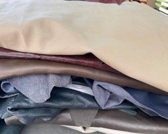 May include: A stack of different colored leather hides, including beige, brown, dark brown, blue, and gray.