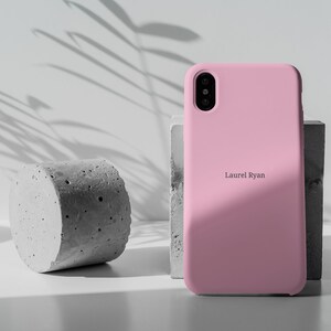 May include: A pink silicone phone case with the name "Laurel Ryan" printed on the back.