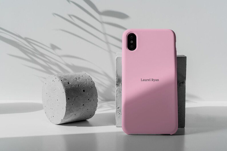 May include: A pink silicone phone case with the name "Laurel Ryan" printed on the back.