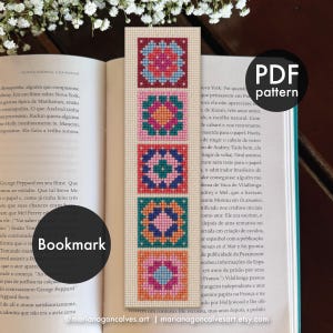 May include: A cross-stitch bookmark pattern featuring five stacked square motifs in vibrant shades of pink, orange, teal, blue, and red on a light beige fabric background. The design is presented as a PDF pattern for a bookmark.