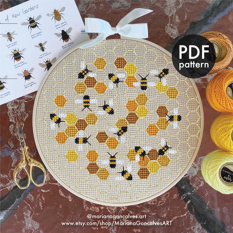 Peut inclure: Un cercle de broderie au point de croix avec un motif d'abeilles et de nids d'abeilles en jaune, marron et noir. Un ruban blanc est nou&eacute; en haut. Le texte "PDF pattern" est visible. Inspir&eacute; des jardins de Kew.