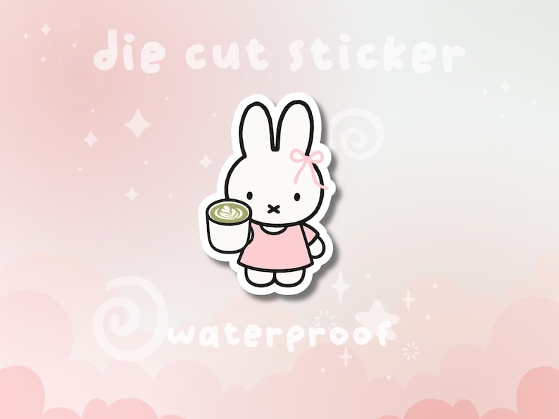 May include: Die cut sticker featuring a white bunny wearing a pink dress and holding a cup of matcha. The sticker has a pink bow and the word "waterproof" is written on the bottom. The background is pink.