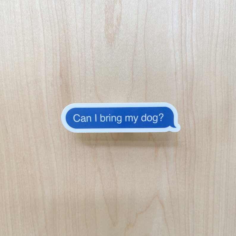 “Can I bring my dog?” sticker centered on light wood background.
