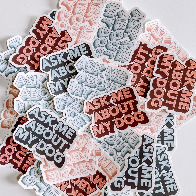 A pile of colorful stickers reading "ASK ME ABOUT MY DOG" in varying shades of blue, red, and pink, conveying a playful and inviting tone.