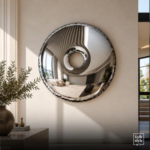 May include: A large, circular, convex wall mirror with a reflective, polished silver surface that creates a distorted, wide-angle view of the room. The mirror features a decorative, scalloped, or wavy dark-toned frame edge. The text Lyfe style art co. is visible in the bottom right corner.