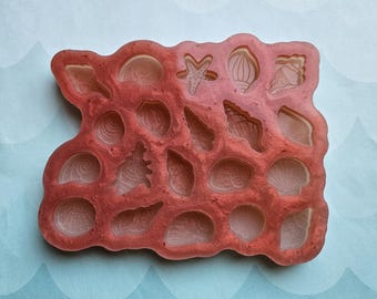 May include: A red silicone mold with 18 different shapes of seashells, starfish, and other ocean-themed designs.