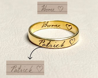 May include: A gold band ring with the words "Home" and "Patrick" engraved on it, each followed by a heart symbol.