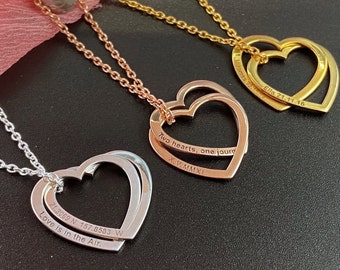 Op de afbeelding: Drie zilveren, gouden en roségouden kettingen met dubbele hart hangers. De zilveren ketting heeft de inscriptie "21.3069 N 157.8583 W Love is in the Air.", de roségouden ketting heeft de inscriptie "Two hearts, one journ X.V.MMXI" en de gouden ketting heeft de inscriptie "Ella 21.11.16".