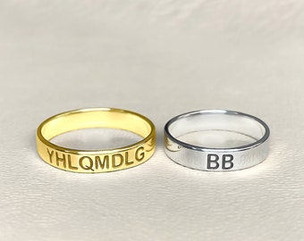 May include: Two simple gold and silver rings with engraved lettering. The gold ring says "YHLQMDLG" and the silver ring says "BB".