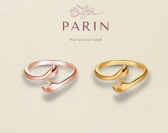 May include: Two adjustable rings with a hand design. The ring on the left is rose gold and the ring on the right is gold.