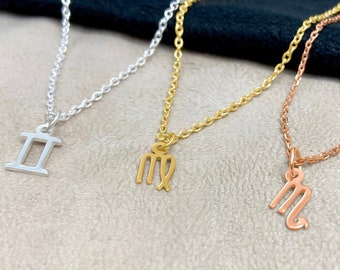 May include: Three gold necklaces with zodiac signs. The necklaces are silver, gold, and rose gold. The signs are Gemini, Virgo, and Scorpio.