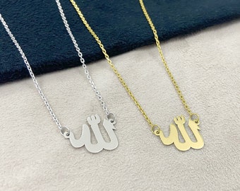 May include: Two silver and gold necklaces with the Arabic word "Allah" pendant. The necklaces are on a light beige surface.