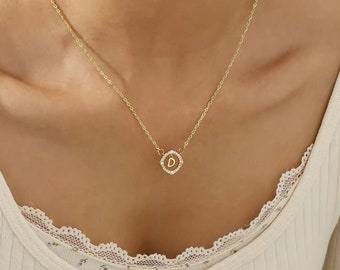 May include: A gold chain necklace with a small pendant featuring the letter "D" surrounded by tiny clear stones.