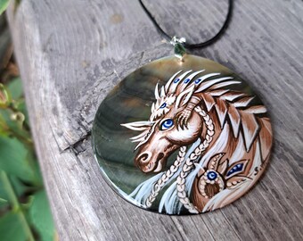 May include: A round pendant necklace featuring a hand-painted fantasy horse design. The horse has brown and white details, blue eyes, and a white mane. The pendant is on a black cord.