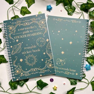 May include: A green and gold reusable sticker book with a celestial theme. The cover features the text "a star traveller's guide to STICKER HOARDING reusable sticker book" and a crescent moon with a lotus flower inside. The back cover is a solid green with a crescent moon and stars.