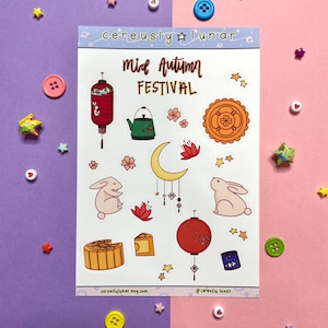 May include: A sheet of Mid-Autumn Festival stickers featuring a variety of designs, including lanterns, mooncakes, rabbits, and a crescent moon. The stickers are on a white background and are surrounded by a pink and purple border.