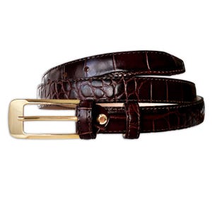 May include: A dark brown belt with a glossy crocodile-embossed texture. The belt features a polished gold-tone rectangular buckle, a matching gold-tone metal keeper loop, and a series of pre-punched holes along the strap for adjustable fastening.