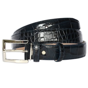 May include: A dark navy blue belt with a glossy crocodile skin texture. The belt features a polished silver-tone metal buckle, a matching leather keeper loop, and a small metal tag near the buckle engraved with the text MADE IN ITALY.