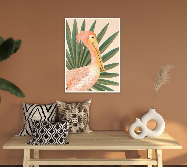 May include: A pink pelican with a long beak is depicted in a watercolor style against a background of green palm leaves. The artwork is framed and displayed on a wall.